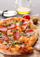 Homemade spicy pepperoni pizza and cooking ingredients. Pepperoni pizza on a gray wooden table.