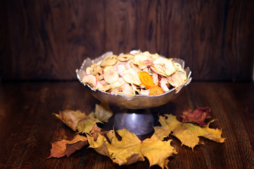 Delicious dried fruits - apples, cherries, crystallized ginger with autumn leaves. Autumn season and harvest concept. Organic Healthy Assorted Dried apple Fruits in metallic bowl. Nutrition and food