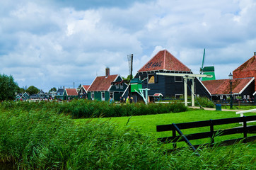Zaanse Schans, Holland, August 2019. Northeast Amsterdam is a small community located on the Zaan River. View between the pretty wooden houses and the blades of the windmills. Very charming.