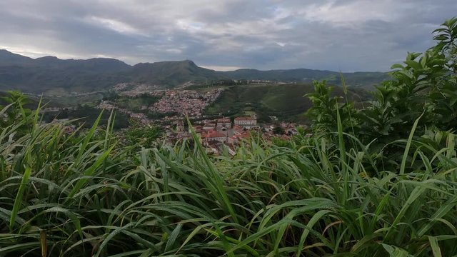 Motion time lapse with morning dew on the grass in the foreground revealing the valley with colonial mining city Ouro Preto in Minas Gerais, Brazil, and its historic streets in the city centre