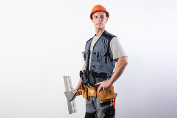 Proud builder with a trowel. In work clothes and hard hat. On a light gray background.