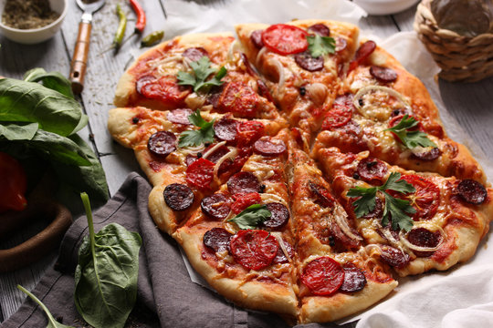Italian cuisine. Pizza with sausages on a wooden background, background image, copy space, pizza with hands.