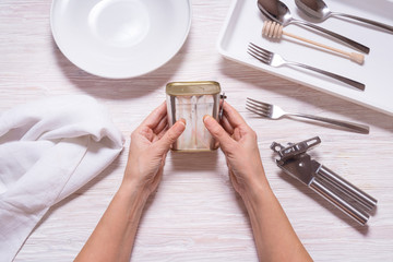 Woman hands opening tin can with corned beef, top view kitchen table
