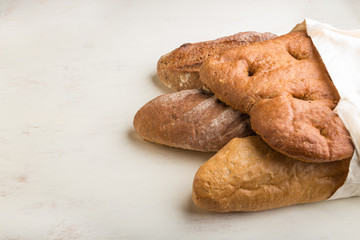 Reusable textile grocery bag with fresh baked bread on a gray concrete background. side view, copy space.