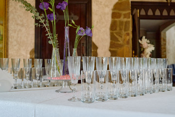 Sparkling glassware and flowers on dinner table in restaurant, copy space. Crystal glasses ready for celebration. Wineglasses at luxury wedding reception