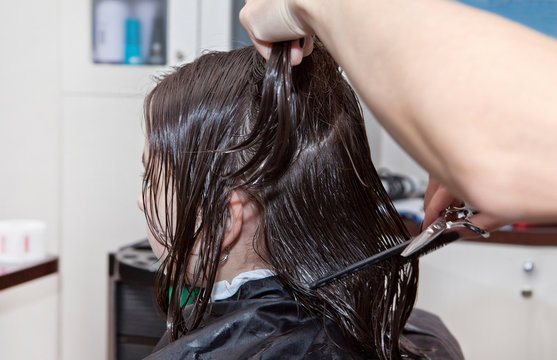 A teenage girl with wet hair during the haircut process in a hair salon.