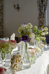 Beautiful floral arrangement on wedding table in restaurant, copy space. Bouquet of pink roses, purple eustoma and greenery in glass vases. Luxury wedding decorations