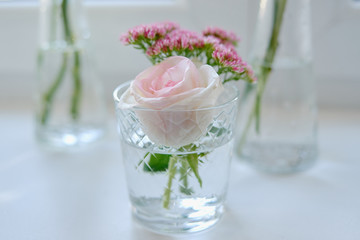 Beautiful floral arrangement on wedding table in restaurant, copy space. Pink rose in glass, close up. Luxury wedding decorations