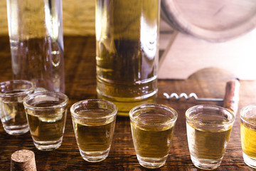 Glass of golden rum, with bottle. Bottle pouring alcohol into a small glass. Brazilian export type drink, glass of alcoholic drinks, cachaça, pinga, distilled drink typical of brazil.
