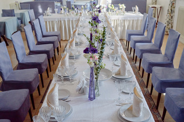 Table setting with white plates, napkins, wineglasses, cutlery and flowers on table, copy space. Place setting at wedding reception. Table served for wedding banquet in restaurant