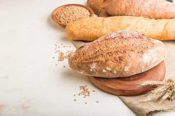 Different kinds of fresh baked bread on a white wooden background. side view, copy space.