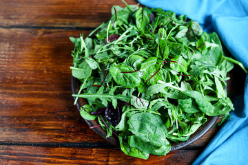 A mixture of green young lettuce, spinach, arugula and young beetroot. Healthy diet. Vegetarian breakfast. On a dark background.
