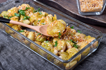Roasted brussels sprouts topped with nut sprinkle in a glass baking dish