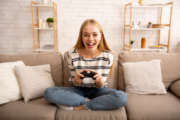 Excited young woman playing video games at home © Prostock-studio