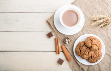 homemade oatmeal cookies with a cup of cocoa on a white wooden background. top view, copy space.