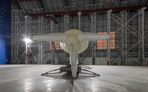 Small blimp on a mooring platform in a giant aircraft hangar. View from the back