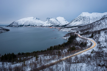 View over Senja in Winter evening with mountains and fjord and lighttrails on the street, Bergsbotn, Norway