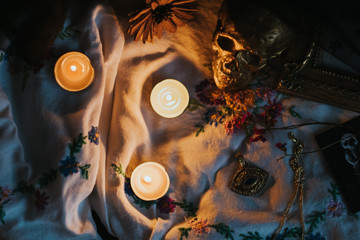 Witchcraft composition with burning candles, jewelry and skull . Halloween and occult concept, black magic ritual.