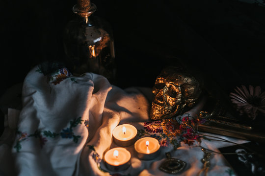 Witchcraft composition with burning candles, jewelry and skull . Halloween and occult concept, black magic ritual.