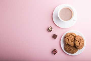 homemade oatmeal cookies with a cup of cocoa on a pink pastel background. top view, copy space.