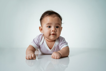 baby laying on her belly. tummy time cute baby in studio portrait on white background