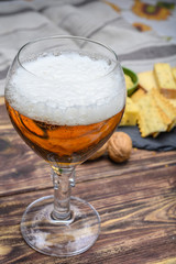 Glass of Belgian abbey blond beer  and stone plate with cheeses made by monks from cow milk with  fenugreek and mustard seeds
