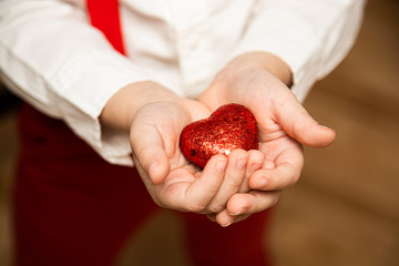 White Caucasian Male, boy holding, giving red glitter sparkle heart. Valentines day. February 14. Love concept 