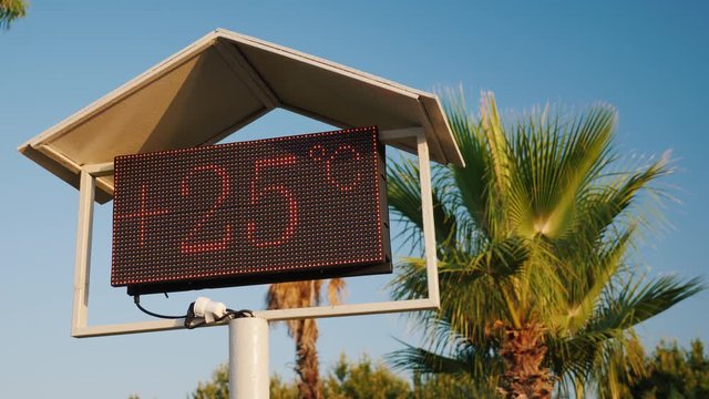 The thermometer's scoreboard on the beach shows the temperature is 25 degrees Celsius