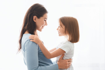 Lovely pregnant mother and daughter cuddling over white background