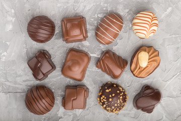 Different chocolate candies on a gray concrete background. top view.