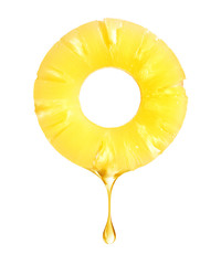 A drop of juice falls from a pineapple ring on a white background