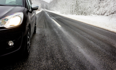 Seitlich gesehenes Auto mit dunkler Straße und Schneelandschaft