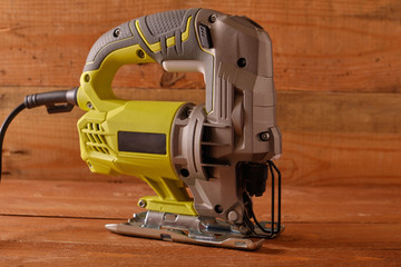 Side view of an electric jigsaw on a wooden workbench