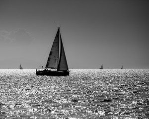 black and white sailing boat silhouette in the high sea on sunset