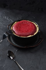 Homemade open red berry pie in baking dish on black background copy space