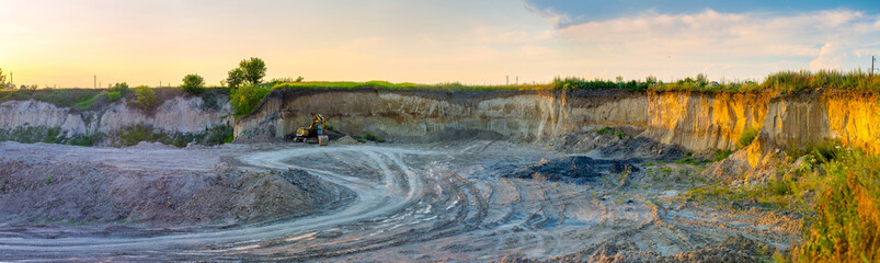 The excavator stands in a clay quarry for a small brick factory. Evening sunshine in industrial...
