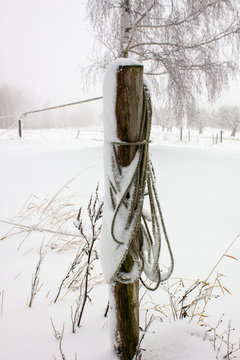 Zaunpflock mit einem Seil und Schnee bedeckt
