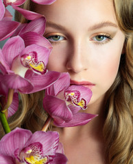 Blonde girl with orchid flowers. Close up face