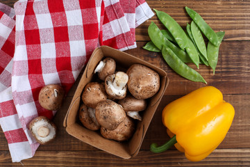 Baby bella mushrooms, yellow bell pepper and snow peas on wooden table