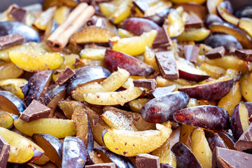 Fresh plum fruit cut into slices, slices with cinnamon sticks, chocolate, cloves. Preparation of ingredients and fruits for making delicious jam.