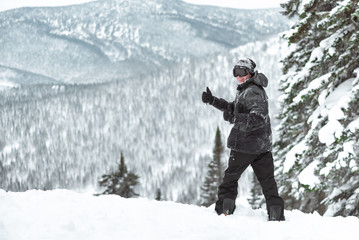 Fototapeta na wymiar Snowboarder with snowboard os showing a thumbs up in the winter forest in the mountains.