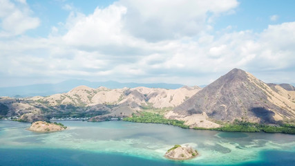 A drone shot of a paradise island with some boats anchored around in Komodo National Park, Flores,...