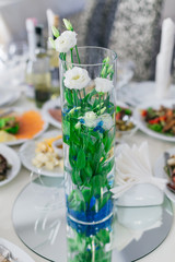 beautiful transparent vase with roses on the table with many dis