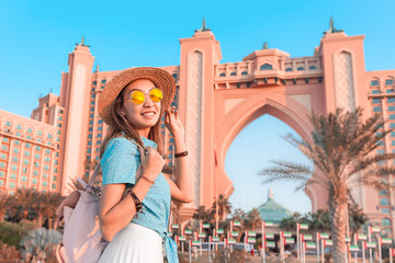 Happy asian girl traveller relaxing near famous luxury Atlantis hotel building on a Jumeirah Palm Island in Duba, UAE