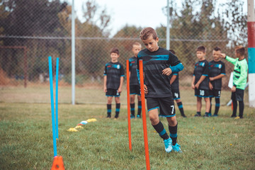 Little soccer player running between cones and ring ladder marker