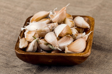 garlic cloves in wooden plate on burlap background