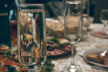 A glass of sparkling champagne on the background of a festive table. A couple of glasses of sparkling wine on a background of salads and shrimp tartlets.