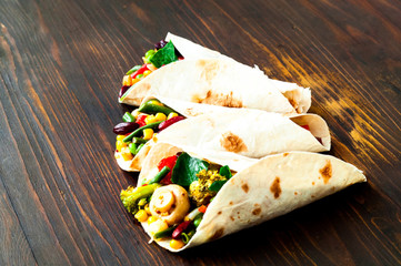 Mexican tortilla with vegetable and mushroom fillings on wooden background. Healthy eating concept. Budget-friendly menu.Close-up