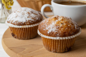 Fresh homemade muffins with sugar powder and a cup of coffee. Close up background