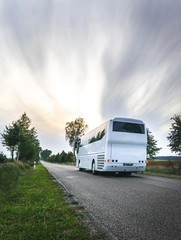White city bus on the road in scenic countryside of Poland. Cloudy day. Excursions in eastern Europe.Dramatic sky. - obrazy, fototapety, plakaty